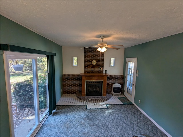 unfurnished living room with carpet, a fireplace, a textured ceiling, ceiling fan, and brick wall