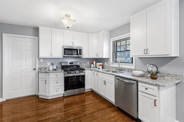 kitchen with white cabinets, light stone counters, dark hardwood / wood-style flooring, appliances with stainless steel finishes, and sink