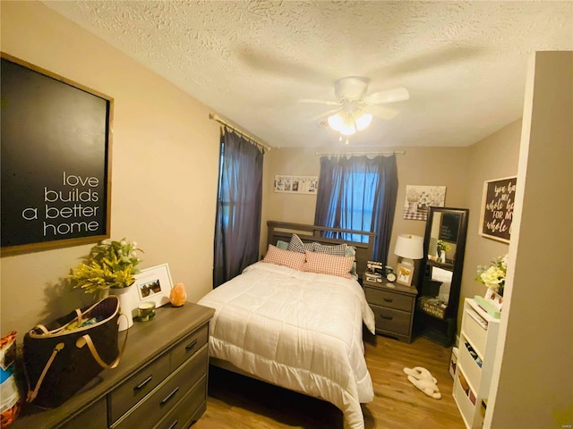 bedroom featuring light hardwood / wood-style floors, a textured ceiling, and ceiling fan