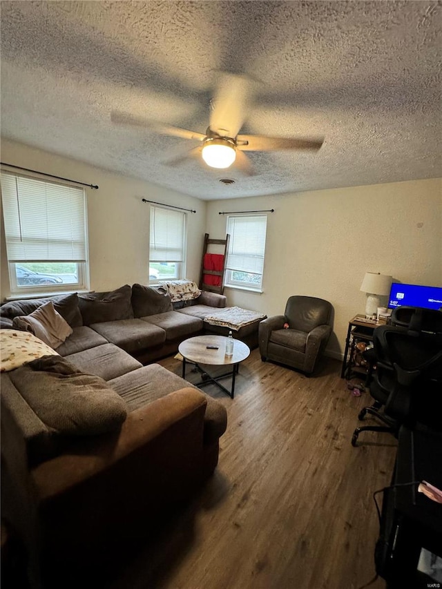 living room featuring hardwood / wood-style flooring, ceiling fan, and a textured ceiling