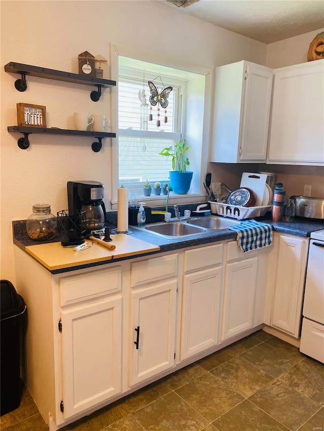 kitchen featuring white cabinets, sink, and white range oven