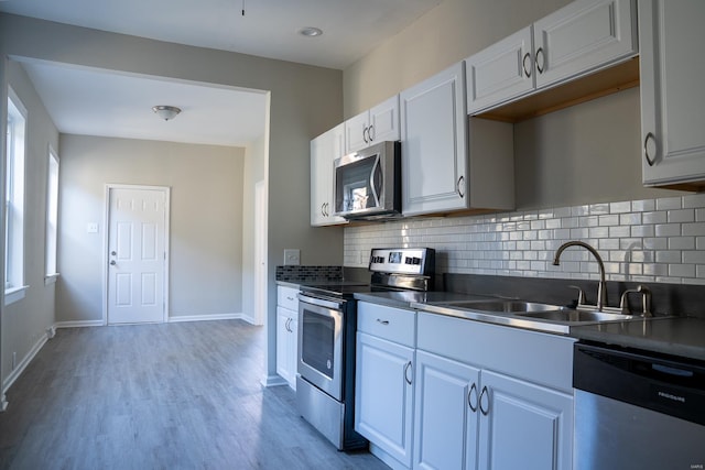 kitchen featuring decorative backsplash, sink, white cabinetry, appliances with stainless steel finishes, and light hardwood / wood-style floors