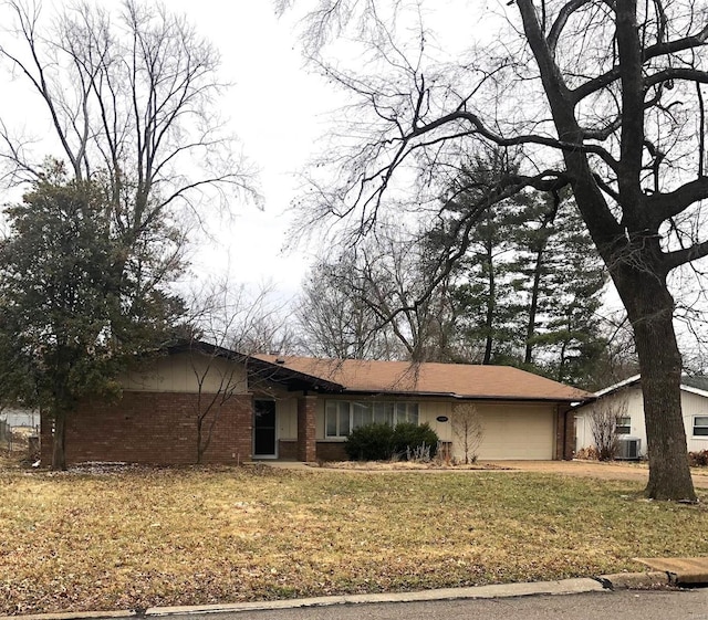 ranch-style home with a garage, brick siding, a front lawn, and central air condition unit