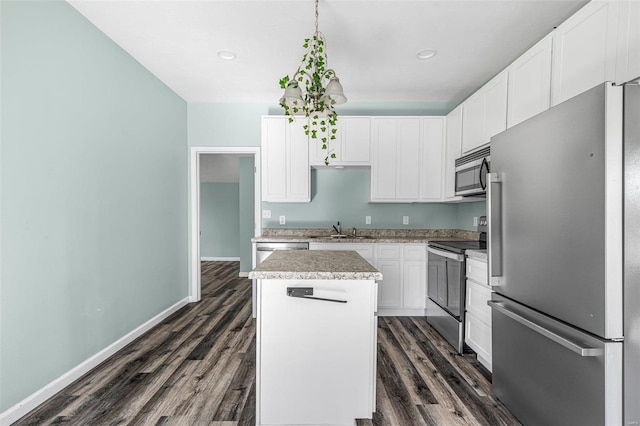 kitchen with white cabinets, dark wood-type flooring, a kitchen island, and appliances with stainless steel finishes