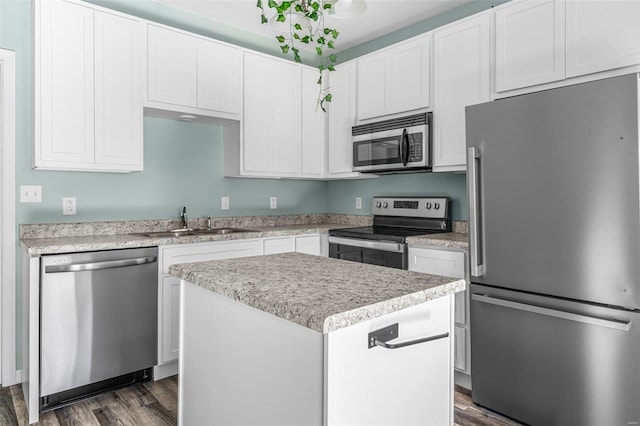 kitchen featuring sink, appliances with stainless steel finishes, dark hardwood / wood-style floors, a center island, and white cabinets