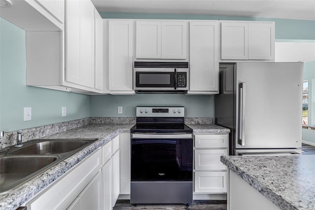 kitchen with stainless steel appliances, white cabinetry, sink, and dark wood-type flooring