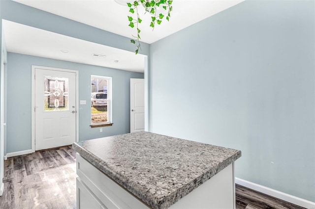 kitchen with white cabinetry, hardwood / wood-style flooring, and a kitchen island