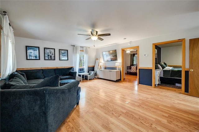 living room featuring ceiling fan, light hardwood / wood-style flooring, and a skylight