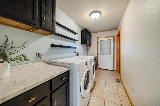 clothes washing area featuring cabinets, light tile patterned flooring, sink, a textured ceiling, and washer and clothes dryer