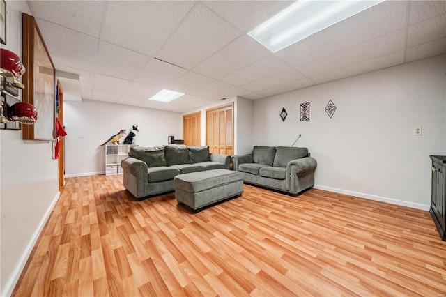 living room with a drop ceiling and light wood-type flooring