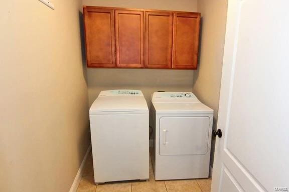 laundry room featuring light tile patterned flooring, separate washer and dryer, and cabinets