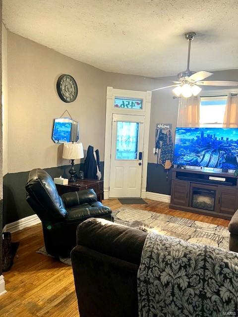 living room with light hardwood / wood-style floors, a textured ceiling, and ceiling fan