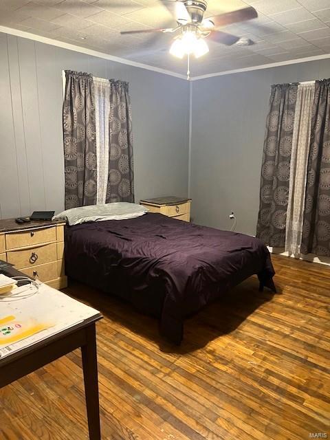 bedroom with crown molding, wood-type flooring, and ceiling fan