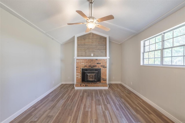 unfurnished living room with ceiling fan, wood-type flooring, vaulted ceiling, and a wood stove