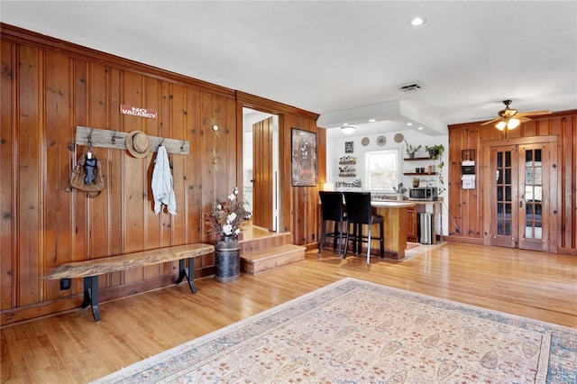 interior space featuring light hardwood / wood-style floors, wood walls, and ceiling fan