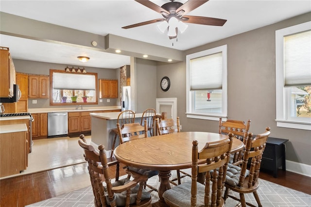 dining area featuring ceiling fan, sink, and light wood-type flooring