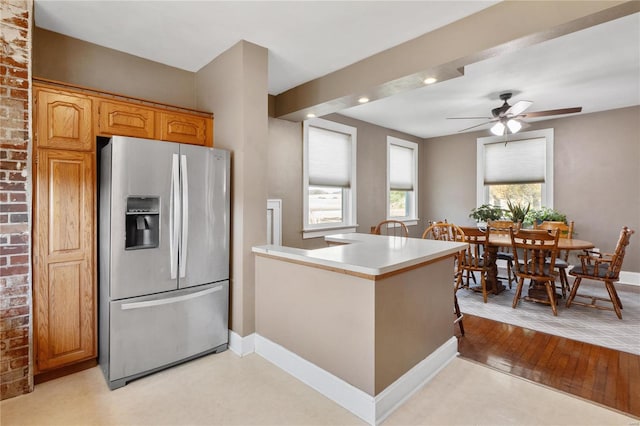 kitchen with kitchen peninsula, stainless steel refrigerator with ice dispenser, light wood-type flooring, and ceiling fan