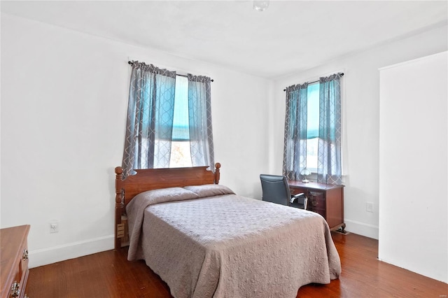 bedroom featuring multiple windows and dark hardwood / wood-style flooring