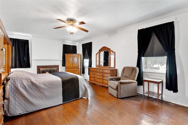 bedroom featuring ceiling fan, hardwood / wood-style flooring, ornamental molding, and a fireplace