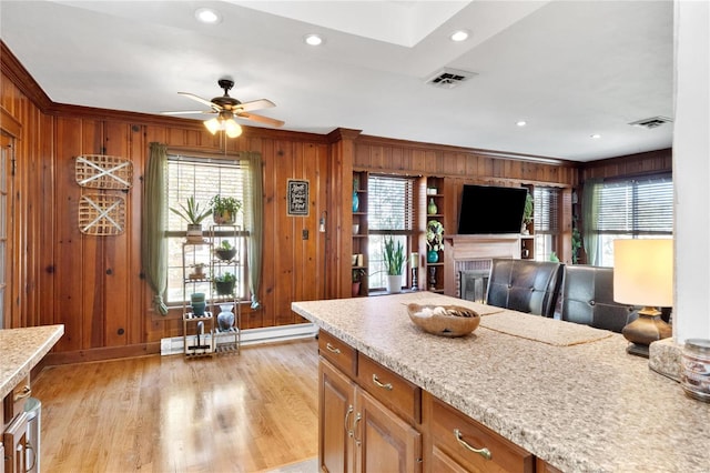 kitchen featuring a baseboard radiator, ceiling fan, wood walls, light hardwood / wood-style floors, and crown molding