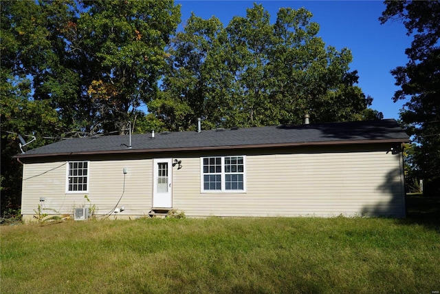 rear view of property featuring central air condition unit and a lawn