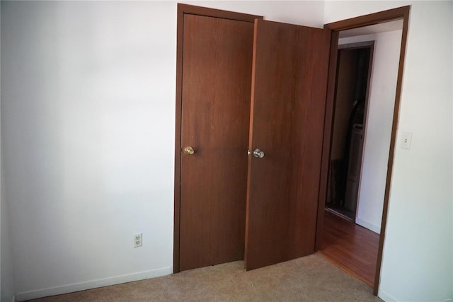 unfurnished bedroom featuring light carpet and a closet