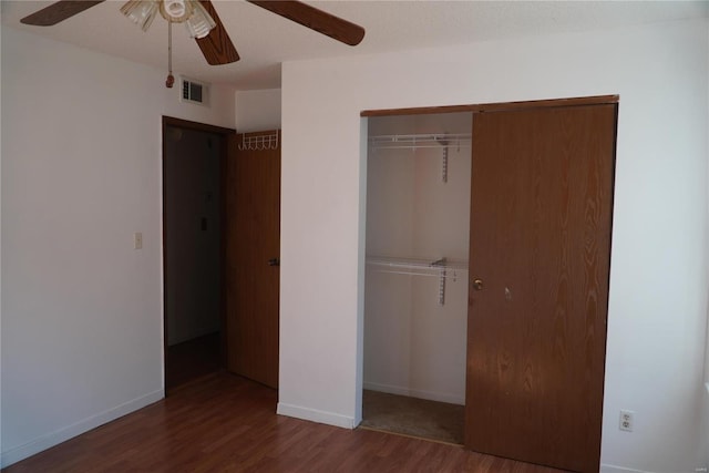 unfurnished bedroom featuring dark hardwood / wood-style flooring, a closet, and ceiling fan