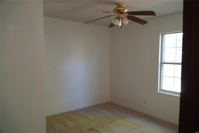 carpeted spare room with a wealth of natural light, a textured ceiling, and ceiling fan