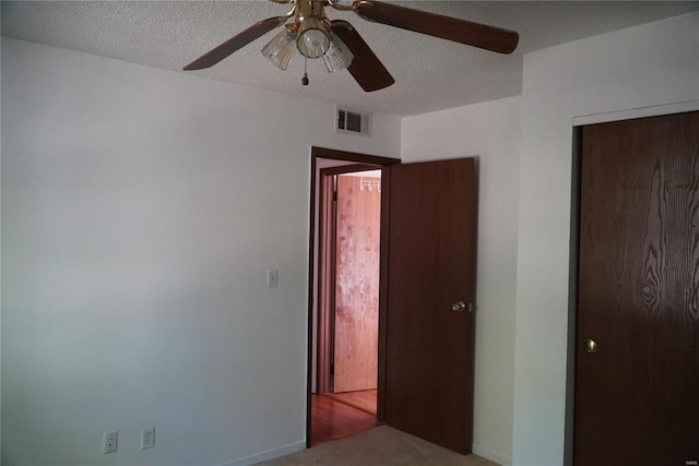 unfurnished bedroom with carpet, ceiling fan, a closet, and a textured ceiling