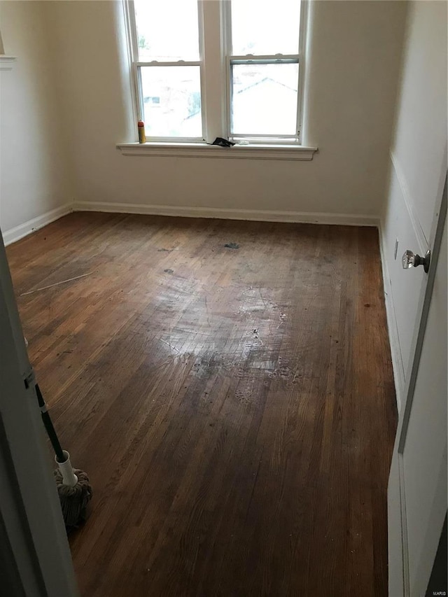 spare room with plenty of natural light and dark wood-type flooring