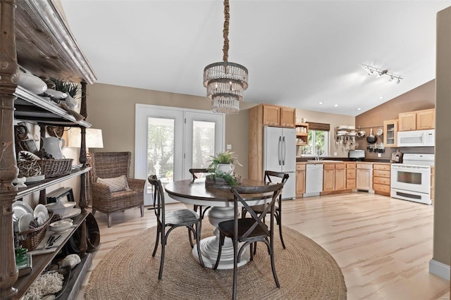 dining space featuring a notable chandelier, vaulted ceiling, and sink