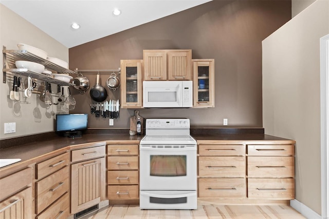 kitchen with light brown cabinetry, white appliances, and lofted ceiling