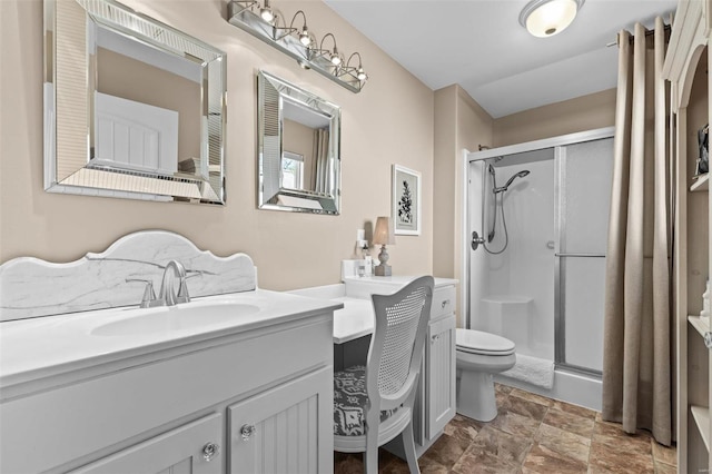 bathroom featuring a shower with door, vanity, and toilet