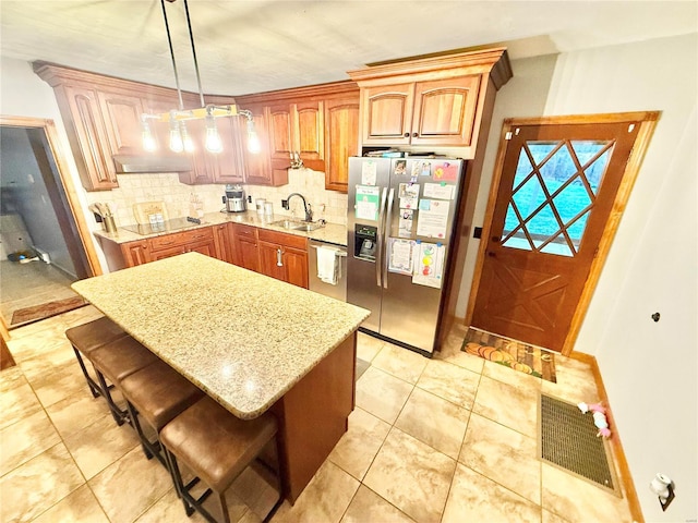 kitchen featuring appliances with stainless steel finishes, a kitchen bar, backsplash, and pendant lighting