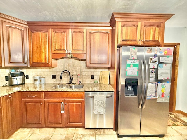 kitchen with sink, light stone counters, stainless steel appliances, and backsplash