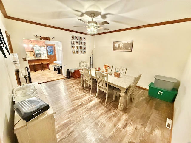 dining space featuring light hardwood / wood-style floors, crown molding, and ceiling fan