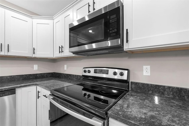 kitchen with appliances with stainless steel finishes, white cabinetry, and dark stone countertops