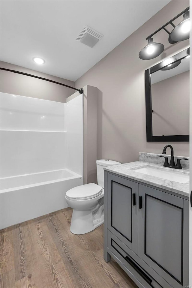 full bathroom with vanity, toilet, wood-type flooring, and shower / tub combination