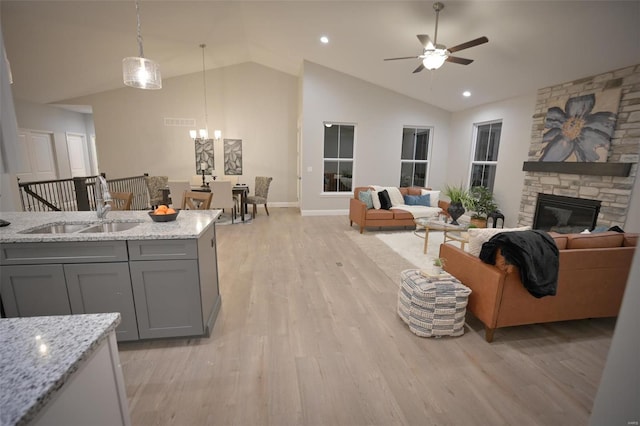 kitchen featuring sink, gray cabinetry, light stone counters, decorative light fixtures, and vaulted ceiling