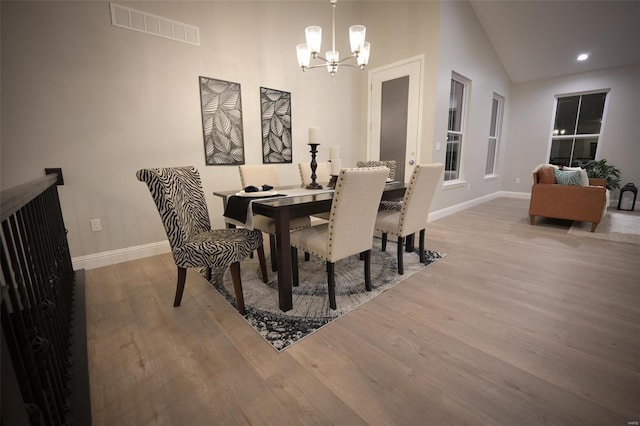 dining area featuring a notable chandelier, vaulted ceiling, and wood-type flooring