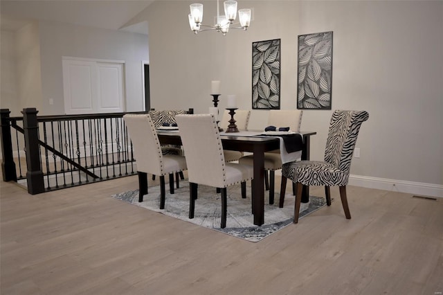 dining room featuring lofted ceiling, a chandelier, and light wood-type flooring