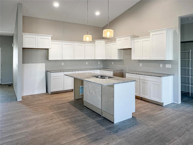 kitchen featuring white cabinetry, light stone countertops, and a center island with sink