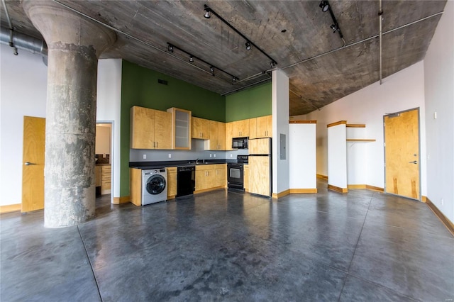 kitchen featuring washer / dryer, a towering ceiling, ornate columns, and black appliances