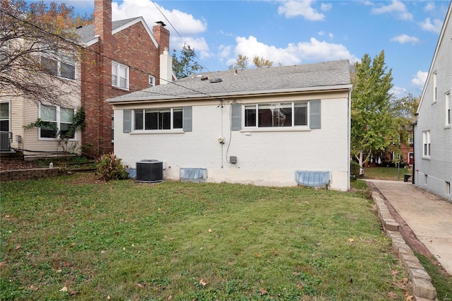 back of house with central AC unit and a lawn