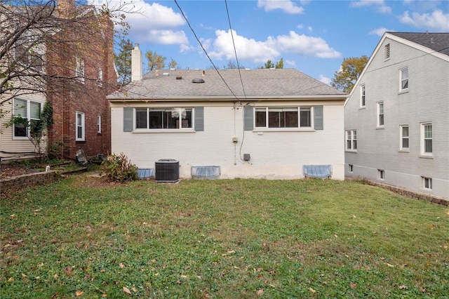 back of property with central AC unit and a yard