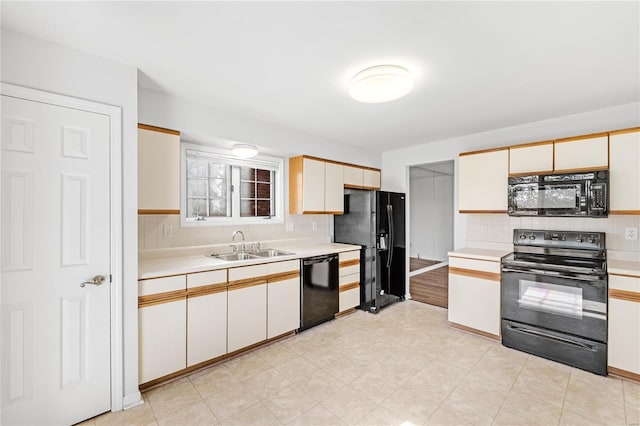 kitchen featuring decorative backsplash, sink, white cabinets, and black appliances