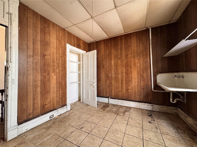 bathroom with a drop ceiling and wood walls