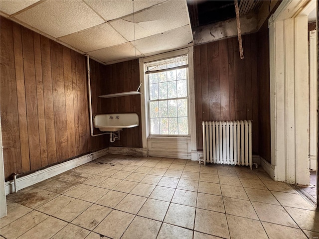 tiled empty room with radiator heating unit and wood walls