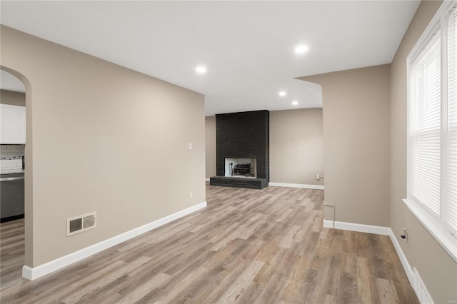 unfurnished living room with light wood-type flooring and a fireplace