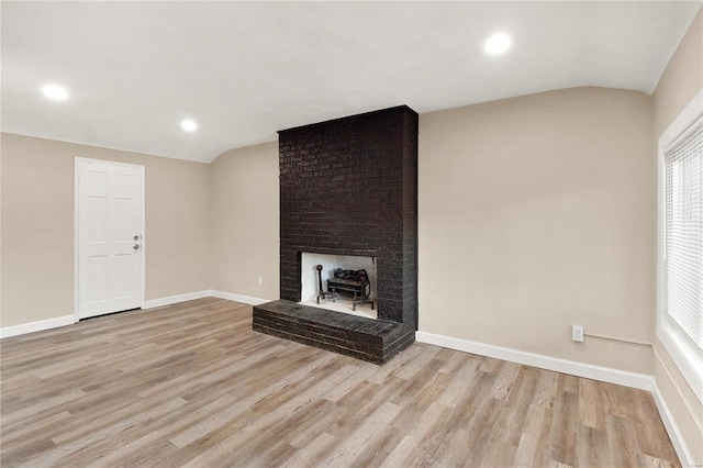 unfurnished living room featuring a fireplace, light hardwood / wood-style floors, and vaulted ceiling